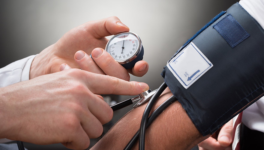 Arzt der den Blutdruck misst mittels eines Blutdruckmessgeräts